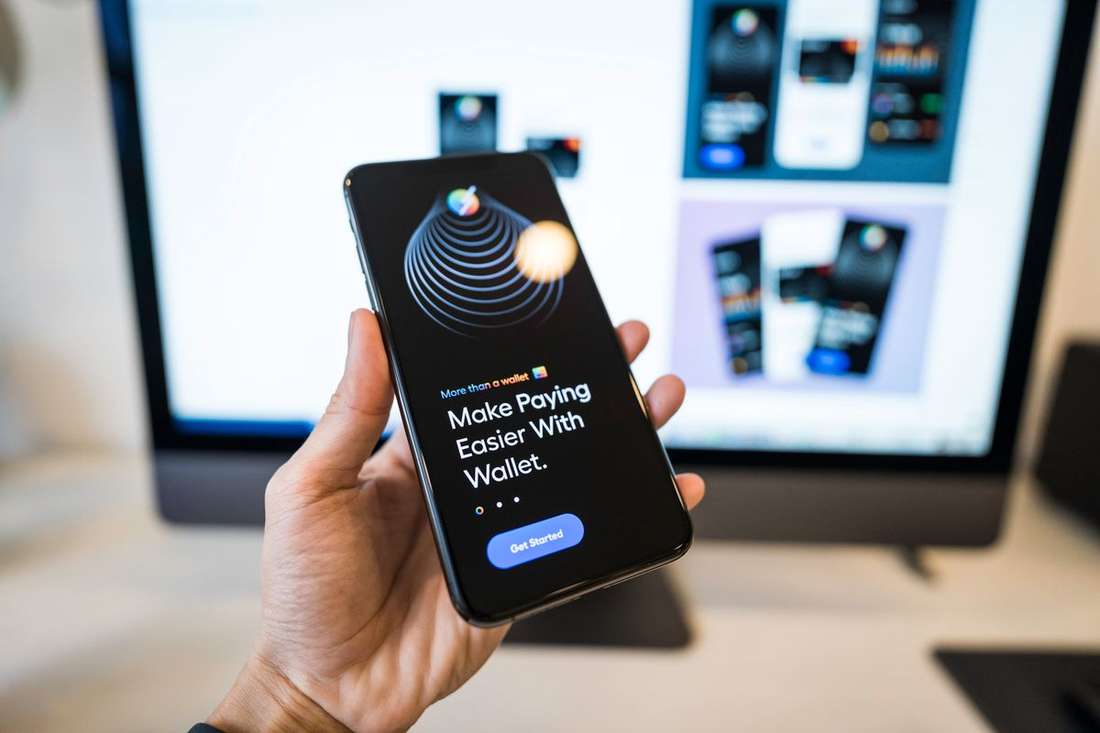 Tangan memegang ponsel menampilkan aplikasi dompet digital